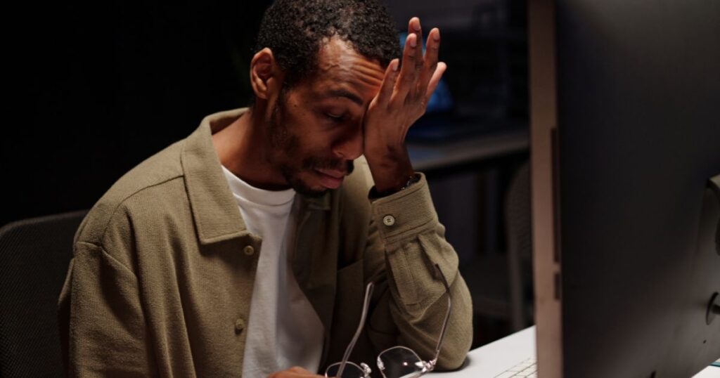 Man putting palm against eyes, rubbing it in agitation in front of screen