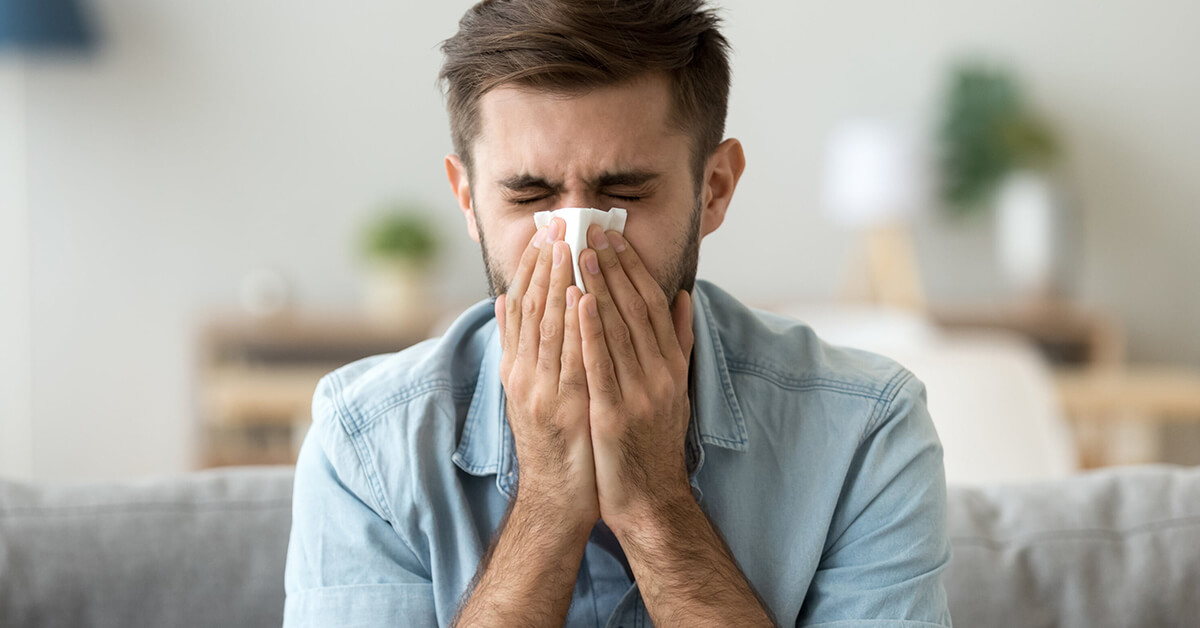 Man with hay fever blowing nose